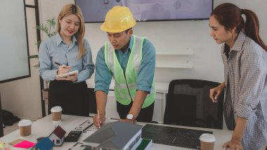 Mimar ve ekibi, bina modeli, mühendis ve takım çalışması ile planlardaki yapısal planların nasıl kontrol edileceği konusunda beyin fırtınası yapmak için inşaat yöneticisiyle görüşüyor.