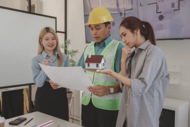 Mimar ve ekibi, bina modeli, mühendis ve takım çalışması ile planlardaki yapısal planların nasıl kontrol edileceği konusunda beyin fırtınası yapmak için inşaat yöneticisiyle görüşüyor.