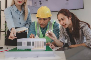 Mimar ve ekibi, bina modeli, mühendis ve takım çalışması ile planlardaki yapısal planların nasıl kontrol edileceği konusunda beyin fırtınası yapmak için inşaat yöneticisiyle görüşüyor.