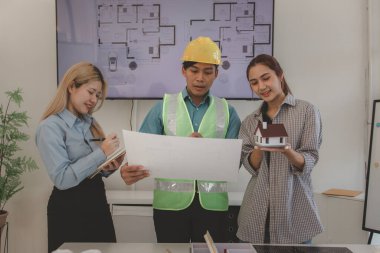 Mimar ve ekibi, bina modeli, mühendis ve takım çalışması ile planlardaki yapısal planların nasıl kontrol edileceği konusunda beyin fırtınası yapmak için inşaat yöneticisiyle görüşüyor.