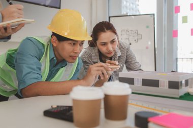 Mimar ve ekibi, bina modeli, mühendis ve takım çalışması ile planlardaki yapısal planların nasıl kontrol edileceği konusunda beyin fırtınası yapmak için inşaat yöneticisiyle görüşüyor.