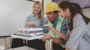 Mimar ve ekibi, bina modeli, mühendis ve takım çalışması ile planlardaki yapısal planların nasıl kontrol edileceği konusunda beyin fırtınası yapmak için inşaat yöneticisiyle görüşüyor.