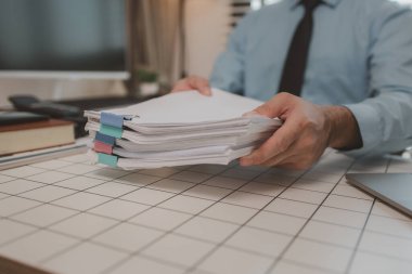 Ofisteki belgelerle bir işadamı ilgileniyor, bir muhasebeci belgeleri topluyor, bir pazarlama müdürü toplantı, finans, girişim, şirket bilgileri hazırlıyor