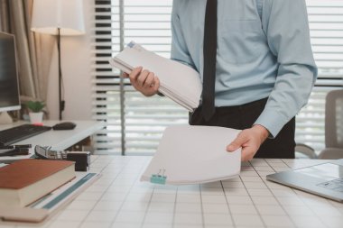 bir işadamı özel ofisinde oturuyor, bir girişimci özenle çalışıyor, baş muhasebeci yöneticilere bir toplantıda sunmak üzere belgeleri ve bütçe rakamlarını gözden geçiriyor