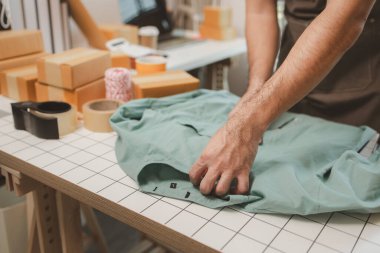 Küçük bir çevrimiçi işletme sahibi müşterilere göndermeden önce doğruluk için kutucukları işaretliyor, paket, bir çalışan müşterilere gönderilmek üzere ürünleri kutulara koyuyor