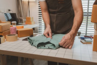 Küçük bir çevrimiçi işletme sahibi müşterilere göndermeden önce doğruluk için kutucukları işaretliyor, paket, bir çalışan müşterilere gönderilmek üzere ürünleri kutulara koyuyor