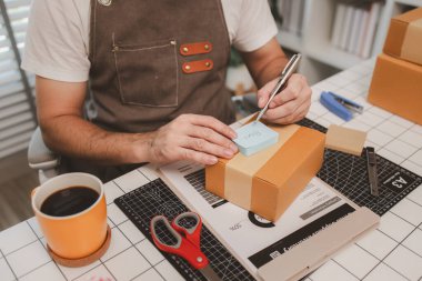 Küçük bir çevrimiçi işletme sahibi müşterilere göndermeden önce doğruluk için kutucukları işaretliyor, paket, bir çalışan müşterilere gönderilmek üzere ürünleri kutulara koyuyor