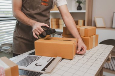 Küçük bir çevrimiçi işletme sahibi müşterilere göndermeden önce doğruluk için kutucukları işaretliyor, paket, bir çalışan müşterilere gönderilmek üzere ürünleri kutulara koyuyor