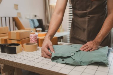 Küçük bir çevrimiçi işletme sahibi müşterilere göndermeden önce doğruluk için kutucukları işaretliyor, paket, bir çalışan müşterilere gönderilmek üzere ürünleri kutulara koyuyor
