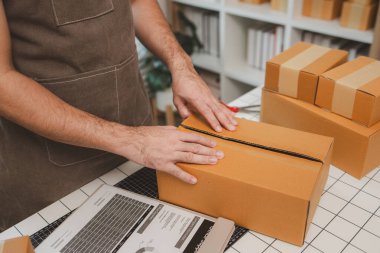 Küçük bir çevrimiçi işletme sahibi müşterilere göndermeden önce doğruluk için kutucukları işaretliyor, paket, bir çalışan müşterilere gönderilmek üzere ürünleri kutulara koyuyor