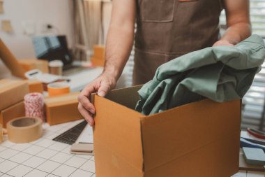 Küçük bir çevrimiçi işletme sahibi müşterilere göndermeden önce doğruluk için kutucukları işaretliyor, paket, bir çalışan müşterilere gönderilmek üzere ürünleri kutulara koyuyor
