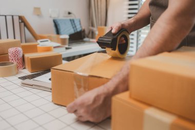 Küçük bir çevrimiçi işletme sahibi müşterilere göndermeden önce doğruluk için kutucukları işaretliyor, paket, bir çalışan müşterilere gönderilmek üzere ürünleri kutulara koyuyor