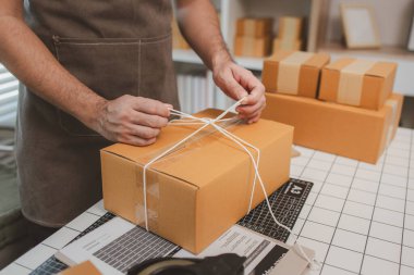 Çalışan, müşterilere nakliyeye hazırlanmak için ürünleri kutulara koyuyor, küçük bir online işletme sahibi müşterilere göndermeden önce doğruluk için kutucukları işaretliyor, paket,