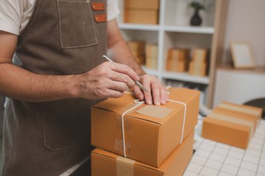 Paketleme odasındaki kutuları kontrol ediyor, küçük bir işletme sahibi kutuları müşterilere, ürünlere, e-ticarete, çevrimiçi satış ve ihracat şirketlerindeki girişimcilere göndermek için hazırlıyor.