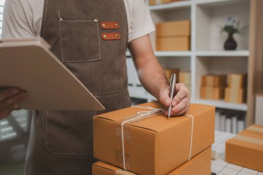 Çalışan, müşterilere nakliyeye hazırlanmak için ürünleri kutulara koyuyor, küçük bir online işletme sahibi müşterilere göndermeden önce doğruluk için kutucukları işaretliyor, paket,