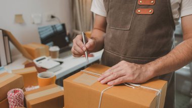 Paketleme odasındaki kutuları kontrol ediyor, küçük bir işletme sahibi kutuları müşterilere, ürünlere, e-ticarete, çevrimiçi satış ve ihracat şirketlerindeki girişimcilere göndermek için hazırlıyor.