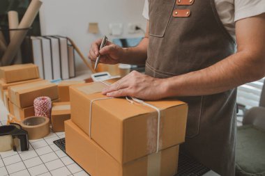 Paketleme odasındaki kutuları kontrol ediyor, küçük bir işletme sahibi kutuları müşterilere, ürünlere, e-ticarete, çevrimiçi satış ve ihracat şirketlerindeki girişimcilere göndermek için hazırlıyor.