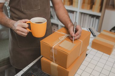 Paketleme odasındaki kutuları kontrol ediyor, küçük bir işletme sahibi kutuları müşterilere, ürünlere, e-ticarete, çevrimiçi satış ve ihracat şirketlerindeki girişimcilere göndermek için hazırlıyor.