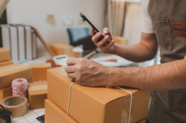 Paketleme odasındaki kutuları kontrol ediyor, küçük bir işletme sahibi kutuları müşterilere, ürünlere, e-ticarete, çevrimiçi satış ve ihracat şirketlerindeki girişimcilere göndermek için hazırlıyor.