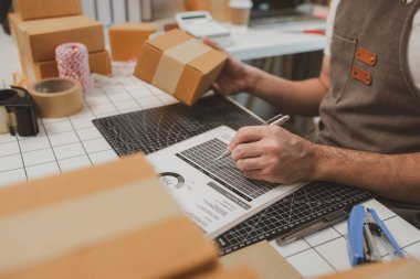 Paketleme odasındaki kutuları kontrol ediyor, küçük bir işletme sahibi kutuları müşterilere, ürünlere, e-ticarete, çevrimiçi satış ve ihracat şirketlerindeki girişimcilere göndermek için hazırlıyor.