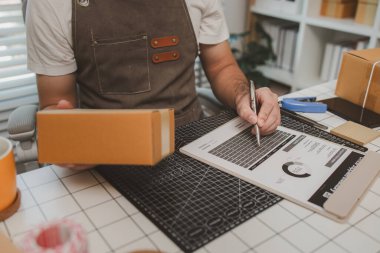 Paketleme odasındaki kutuları kontrol ediyor, küçük bir işletme sahibi kutuları müşterilere, ürünlere, e-ticarete, çevrimiçi satış ve ihracat şirketlerindeki girişimcilere göndermek için hazırlıyor.