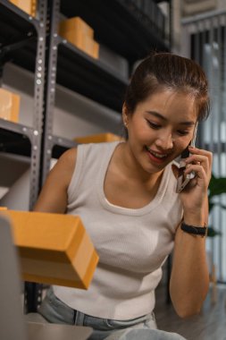 Paketleyici, bir müşteriye teslim edilmeden önce paketin durumunu kontrol eder, küçük bir işletme sahibi bir depodaki kutuları inceler, raflarla dolu bir depo ve paket