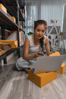 Bir bayan çalışan depodaki paket kutularını kontrol ediyor, bir depo müdürü raflardaki paket kutularını sayıyor, küçük bir online işletme sahibi bir depo odasında.