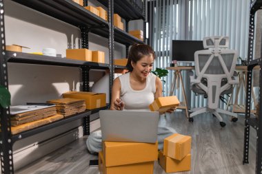 Bir bayan çalışan depodaki paket kutularını kontrol ediyor, bir depo müdürü raflardaki paket kutularını sayıyor, küçük bir online işletme sahibi bir depo odasında.