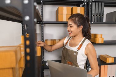 Depodaki paket kutularıyla çalışan bir çalışan depodaki paket kutularının sayısını kontrol eder. Nakliye işindeki bir girişimci depoyu teftiş etmek için gelir.