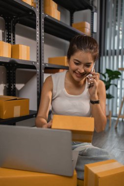 Paketleyici, bir müşteriye teslim edilmeden önce paketin durumunu kontrol eder, küçük bir işletme sahibi bir depodaki kutuları inceler, raflarla dolu bir depo ve paket