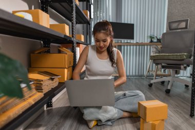 Bir bayan çalışan depodaki paket kutularını kontrol ediyor, bir depo müdürü raflardaki paket kutularını sayıyor, küçük bir online işletme sahibi bir depo odasında.