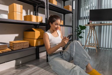 Bir bayan çalışan depodaki paket kutularını kontrol ediyor, bir depo müdürü raflardaki paket kutularını sayıyor, küçük bir online işletme sahibi bir depo odasında.