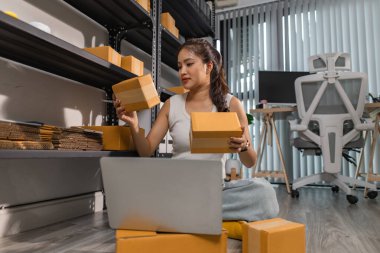 Bir bayan çalışan depodaki paket kutularını kontrol ediyor, bir depo müdürü raflardaki paket kutularını sayıyor, küçük bir online işletme sahibi bir depo odasında.