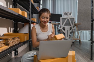 Bir bayan çalışan depodaki paket kutularını kontrol ediyor, bir depo müdürü raflardaki paket kutularını sayıyor, küçük bir online işletme sahibi bir depo odasında.