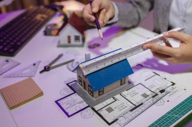 Tecrübeli bir kadın mühendis, özel ofisindeki bir ev modeline son bir çek veriyor. Planlara uyduğundan ve inşaatın bitiş tarihine yetiştiğinden emin olmak için.