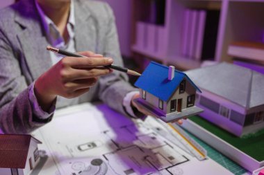 Tecrübeli bir kadın mühendis, özel ofisindeki bir ev modeline son bir çek veriyor. Planlara uyduğundan ve inşaatın bitiş tarihine yetiştiğinden emin olmak için.