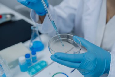 Bir kadın bilim adamı laboratuvarda çalışıyor, bir kimyager laboratuarda sıvı örneği test ediyor, laboratuarda çalışırken önlük giyiyor, test tüpü, bilimsel ekipman.