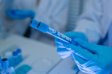 Laboratuvarda bilim adamları laboratuvar önlükleri, lastik eldivenler ve güvenlik gözlükleri takarken, iki kimyager sıvı haldeki kimyasalları test ediyor, kimyagerler laboratuarda çalışıyor.