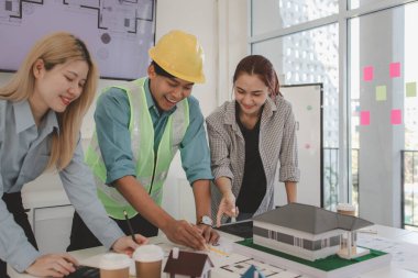 Mimar ve ekibi, bina modeli, mühendis ve takım çalışması ile planlardaki yapısal planların nasıl kontrol edileceği konusunda beyin fırtınası yapmak için inşaat yöneticisiyle görüşüyor.