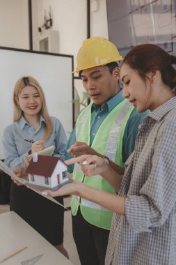 Mimar ve ekibi, bina modeli, mühendis ve takım çalışması ile planlardaki yapısal planların nasıl kontrol edileceği konusunda beyin fırtınası yapmak için inşaat yöneticisiyle görüşüyor.