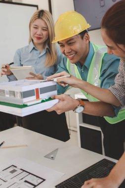 Mimar ve ekibi, bina modeli, mühendis ve takım çalışması ile planlardaki yapısal planların nasıl kontrol edileceği konusunda beyin fırtınası yapmak için inşaat yöneticisiyle görüşüyor.