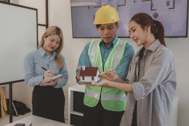 Mimar ve ekibi, bina modeli, mühendis ve takım çalışması ile planlardaki yapısal planların nasıl kontrol edileceği konusunda beyin fırtınası yapmak için inşaat yöneticisiyle görüşüyor.