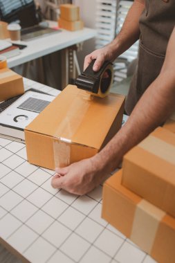 Küçük bir çevrimiçi işletme sahibi müşterilere göndermeden önce doğruluk için kutucukları işaretliyor, paket, bir çalışan müşterilere gönderilmek üzere ürünleri kutulara koyuyor