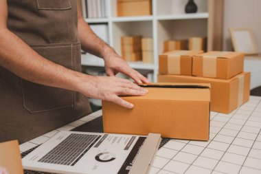 Küçük bir çevrimiçi işletme sahibi müşterilere göndermeden önce doğruluk için kutucukları işaretliyor, paket, bir çalışan müşterilere gönderilmek üzere ürünleri kutulara koyuyor