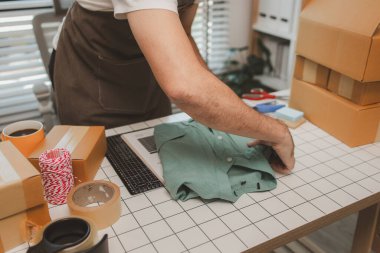 Küçük bir çevrimiçi işletme sahibi müşterilere göndermeden önce doğruluk için kutucukları işaretliyor, paket, bir çalışan müşterilere gönderilmek üzere ürünleri kutulara koyuyor