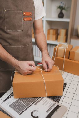 Küçük bir çevrimiçi işletme sahibi müşterilere göndermeden önce doğruluk için kutucukları işaretliyor, paket, bir çalışan müşterilere gönderilmek üzere ürünleri kutulara koyuyor