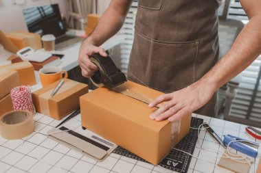Çalışan, müşterilere nakliyeye hazırlanmak için ürünleri kutulara koyuyor, küçük bir online işletme sahibi müşterilere göndermeden önce doğruluk için kutucukları işaretliyor, paket,