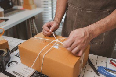 Çalışan, müşterilere nakliyeye hazırlanmak için ürünleri kutulara koyuyor, küçük bir online işletme sahibi müşterilere göndermeden önce doğruluk için kutucukları işaretliyor, paket,