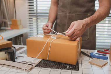 Çalışan, müşterilere nakliyeye hazırlanmak için ürünleri kutulara koyuyor, küçük bir online işletme sahibi müşterilere göndermeden önce doğruluk için kutucukları işaretliyor, paket,