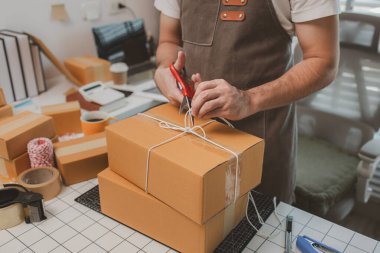Çalışan, müşterilere nakliyeye hazırlanmak için ürünleri kutulara koyuyor, küçük bir online işletme sahibi müşterilere göndermeden önce doğruluk için kutucukları işaretliyor, paket,